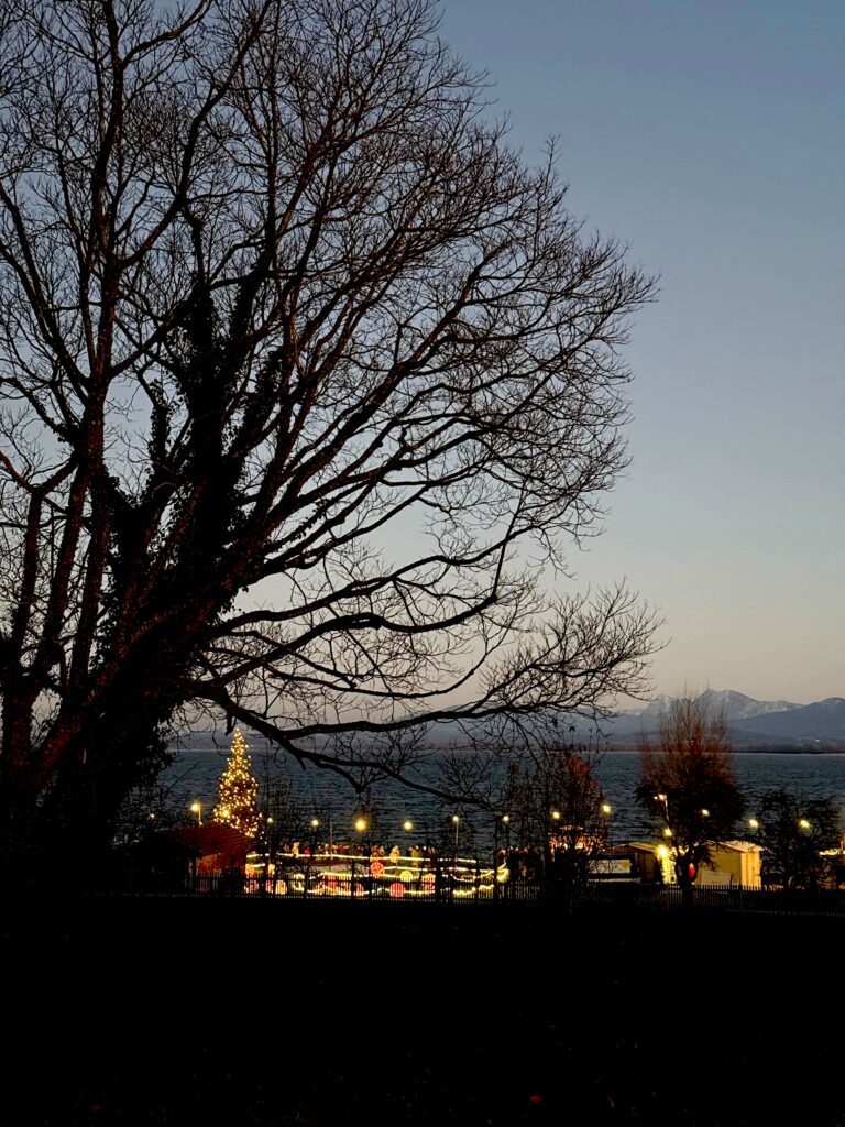 Stimmungsvoller Weihnachtsmarkt auf der Fraueninsel am Ufer des Chiemsees mit Blick auf die Alpen