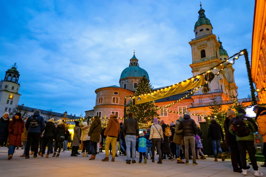 Menschen und Tannenbäume auf dem Weihnachtsmarkt in Salzburg in der Dämmerung